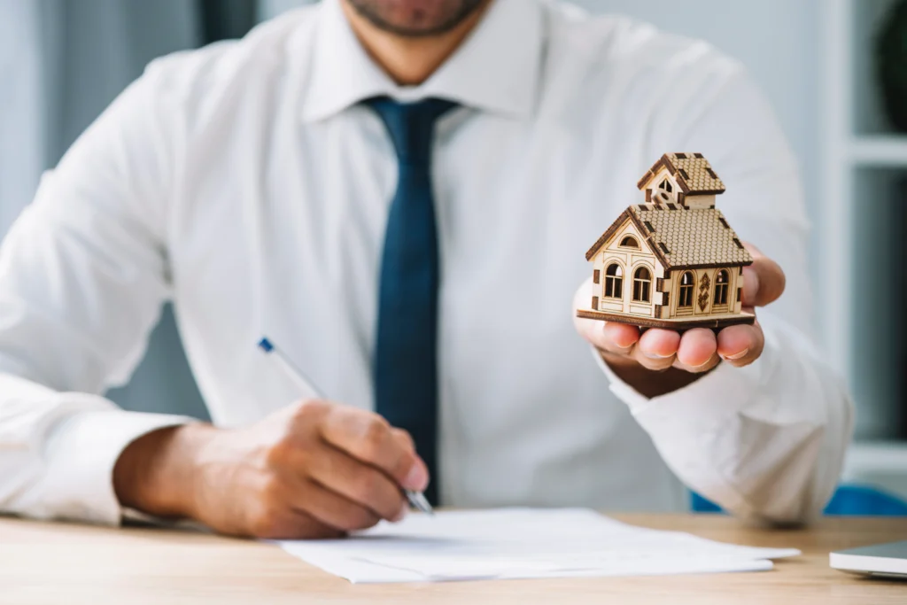 Man holding house model, signing documents